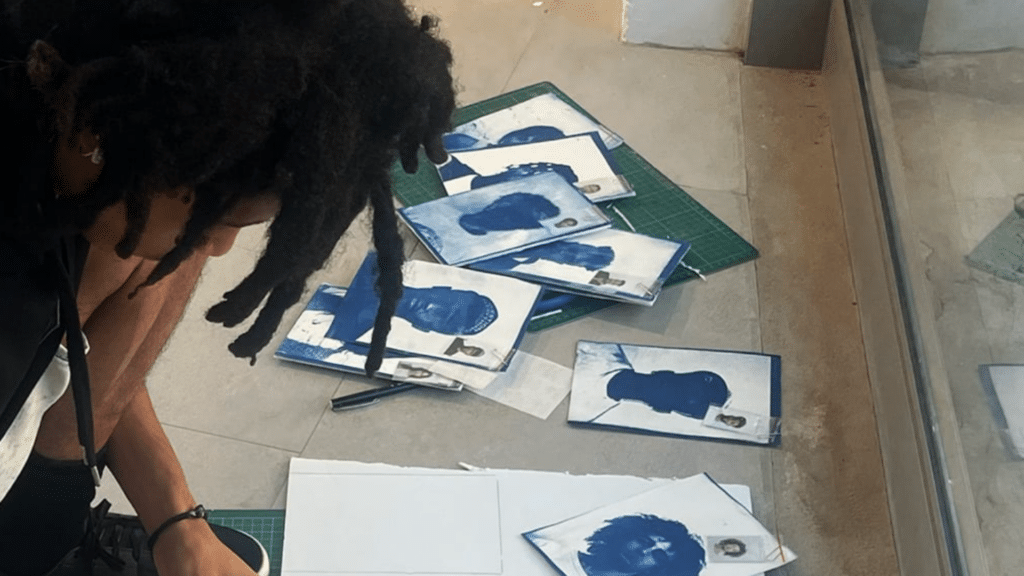 A cape town creative academy student, carefully organising blue cyanotype photographic prints and portraits.
