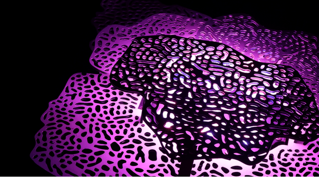 Abstract purple perforated metal sheets lit with magenta light against a black background.